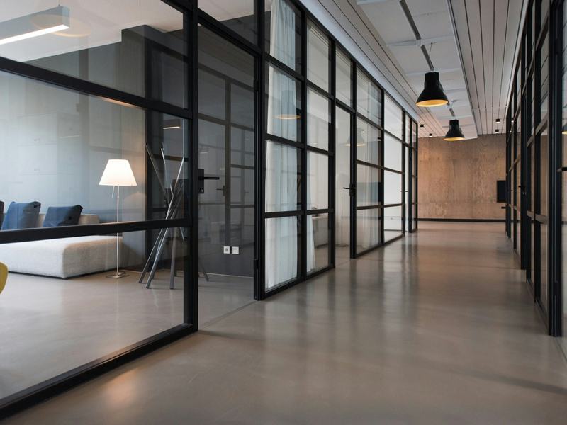 Corredor de um escritório corporativo contemporâneo com salas envidraçadas.